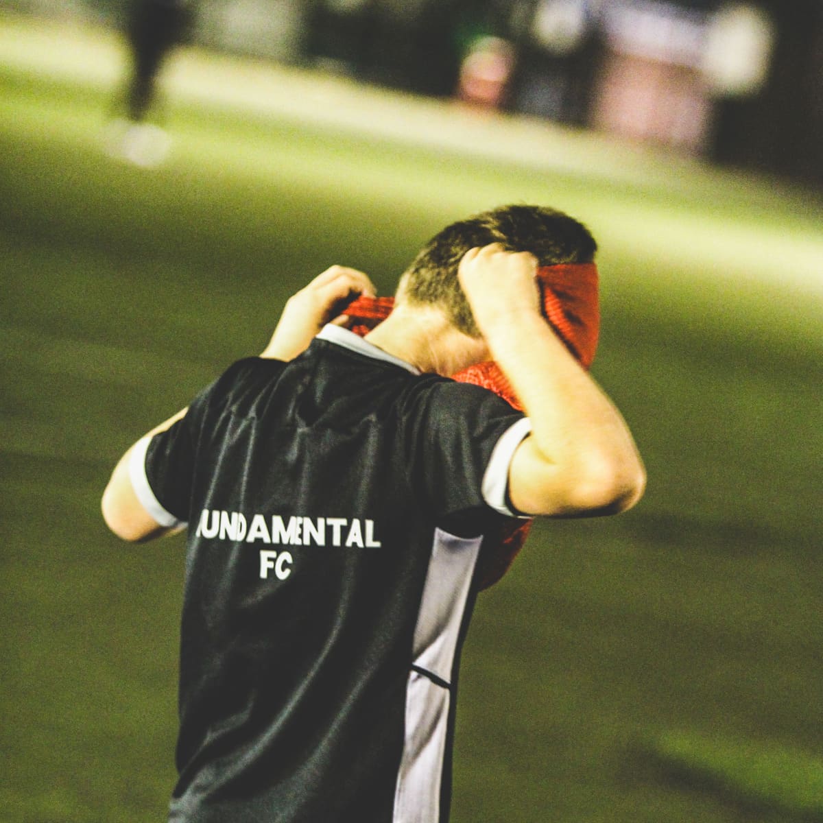 A player in Fundamental FC kit at a floodlit training session