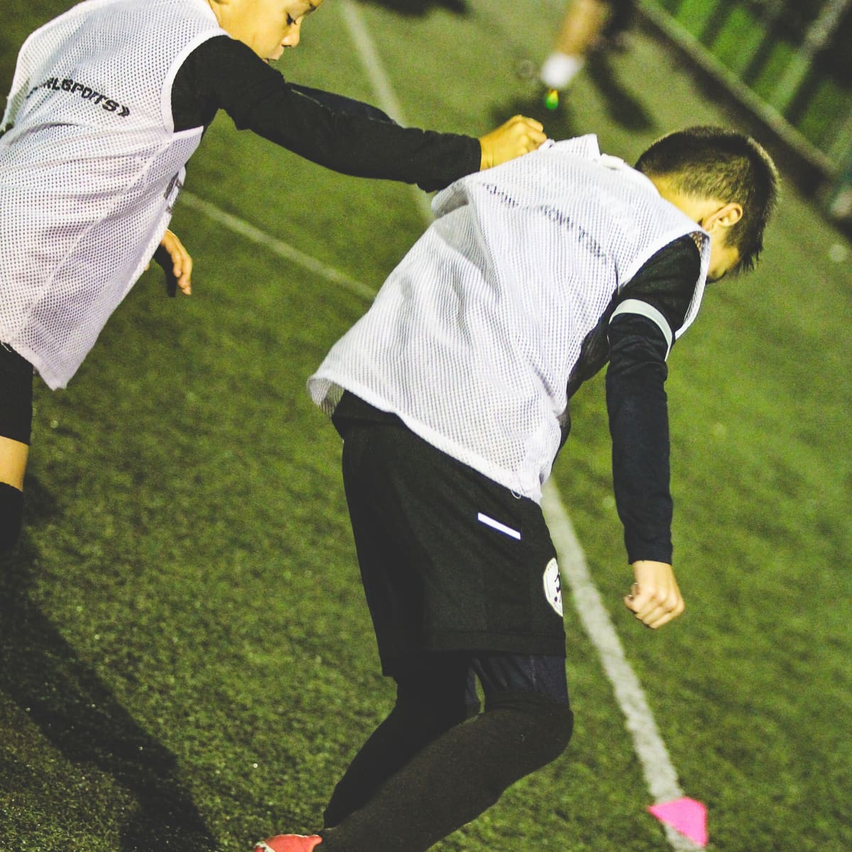 Two players in training bibs challenging for the ball